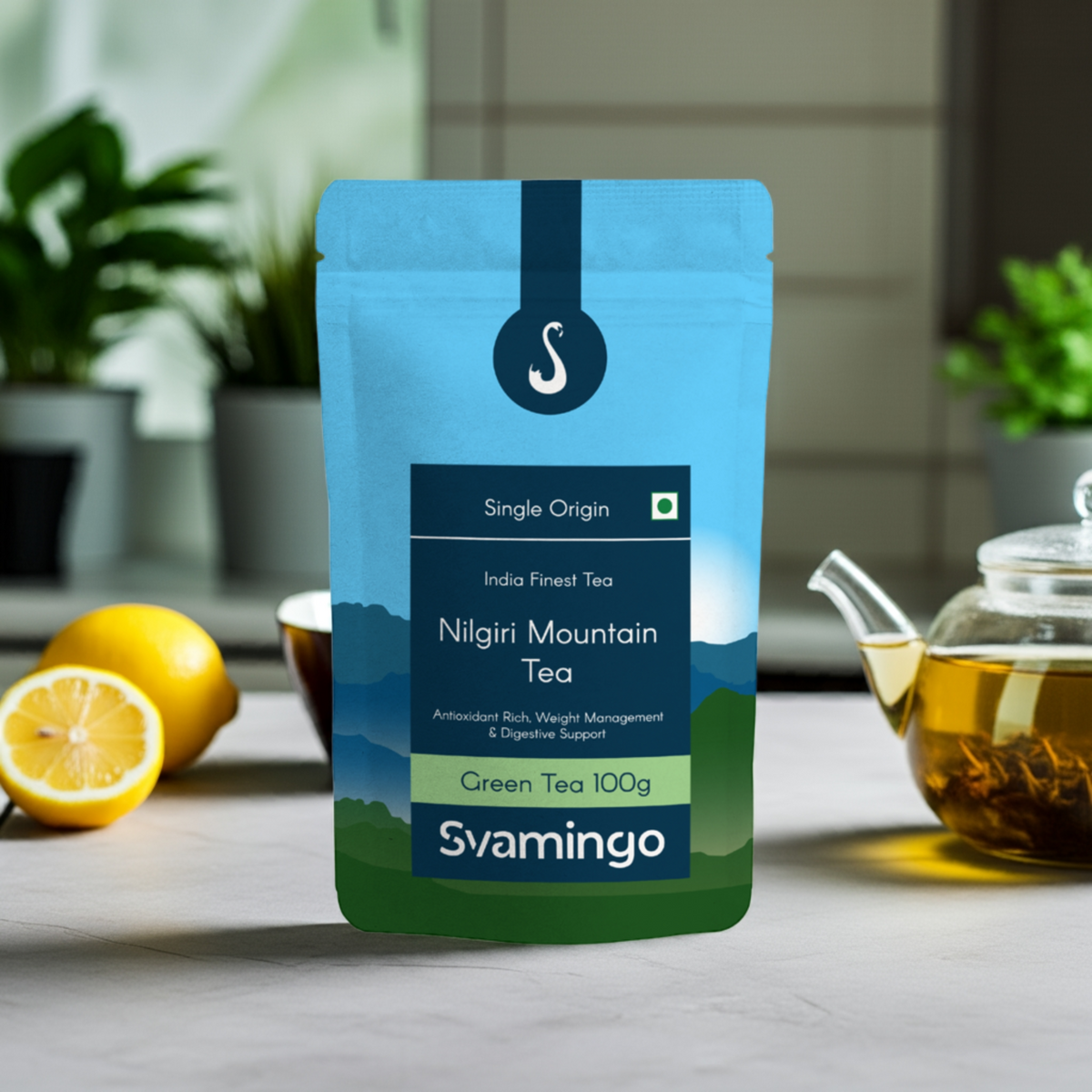 Svamingo nilgiri green tea pouch 100g on a marble table in kitchen with lemons, tea cups, green tea pot on the side